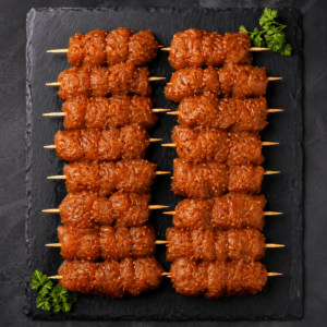 Unfried marinated chicken sticks skewers arranged on black slate board premium frozen food product Pak N Pure